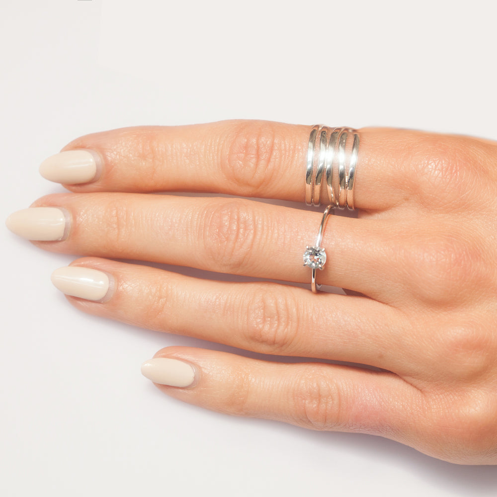 Hand with wide silver multiple banded wrap ring and solitaire ring