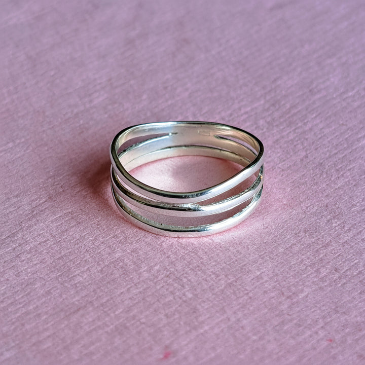 Sterling silver wrap ring on a pink background
