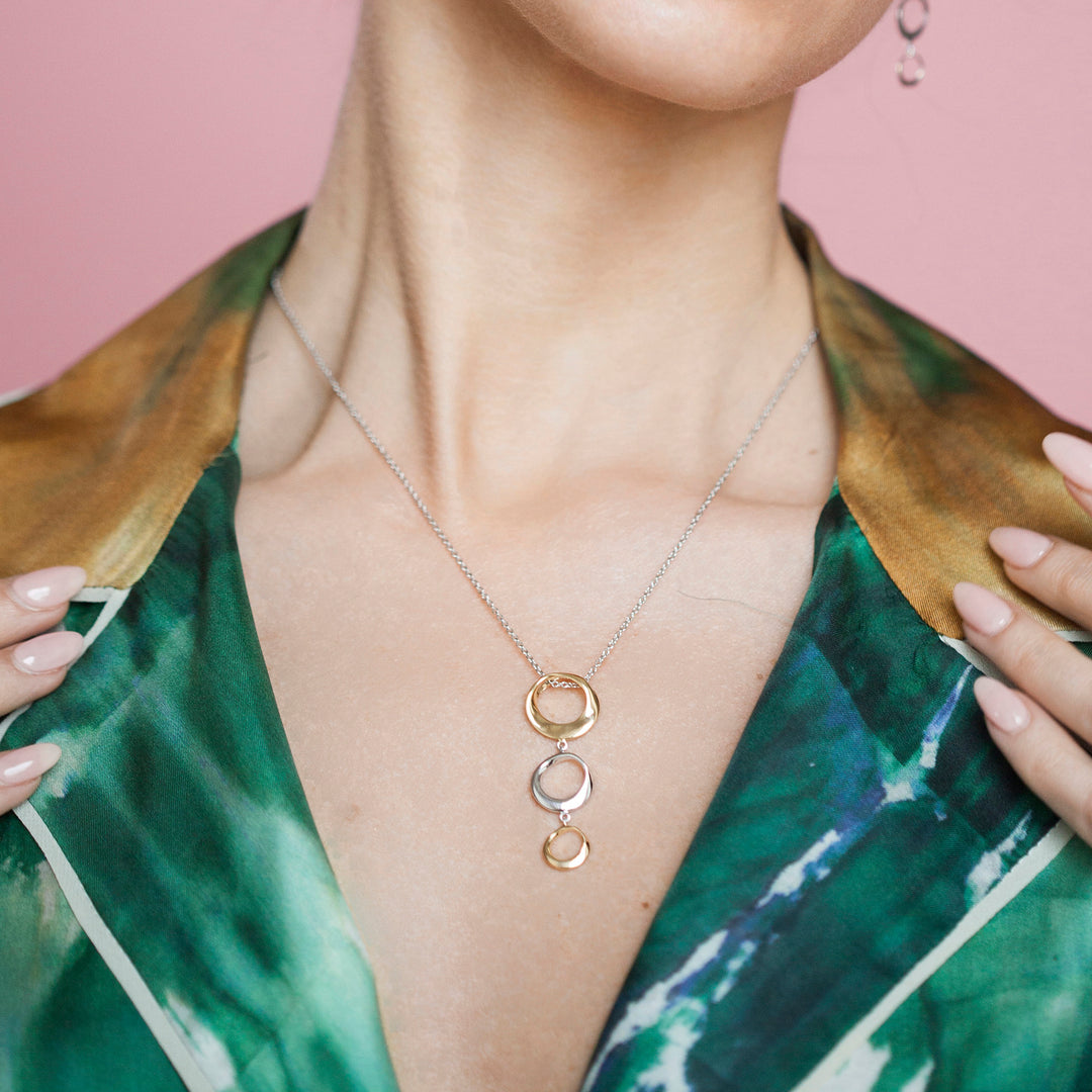 Close-up of model wearing silver and gold three ring necklace
