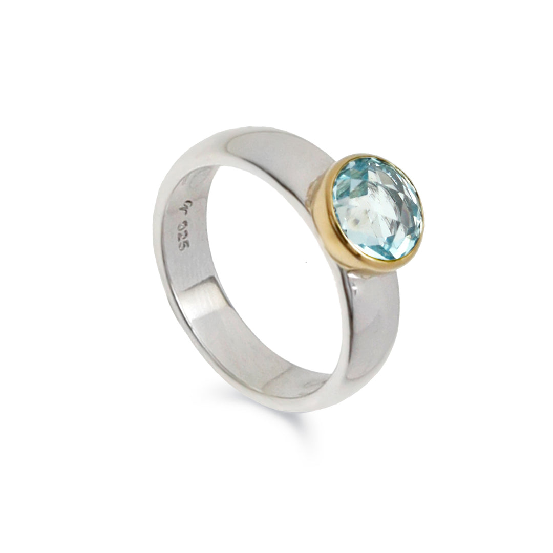 Silver ring with a gold accent and blue gemstone on a white background
