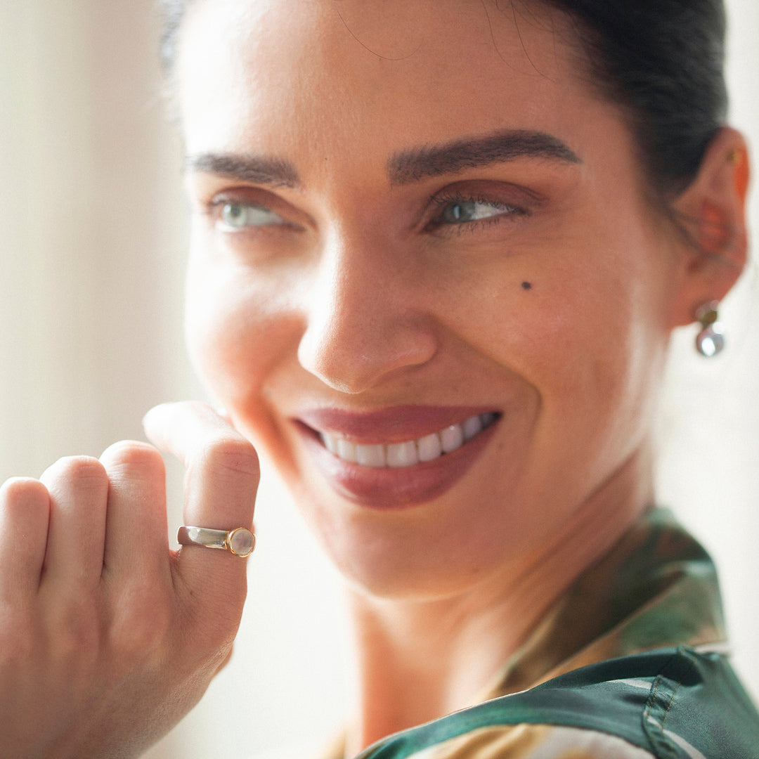 Model wearing a silver, gold and moonstone ring in sunlight