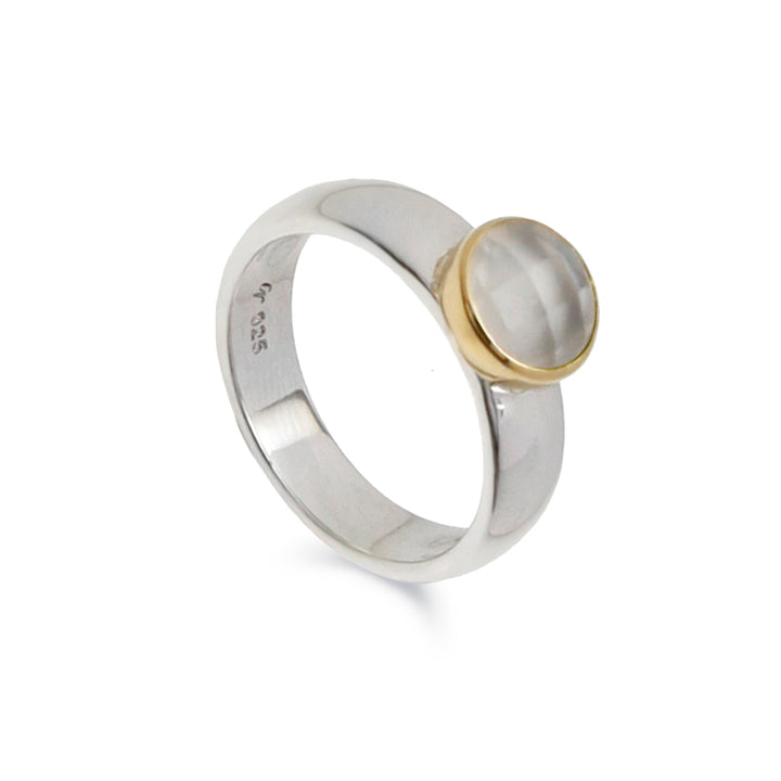 Silver band ring with a round moonstone set in a gold bezel on a white background