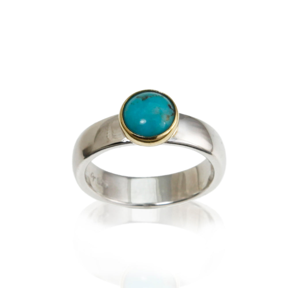 Silver and gold ring with a round turquoise stone on a white background