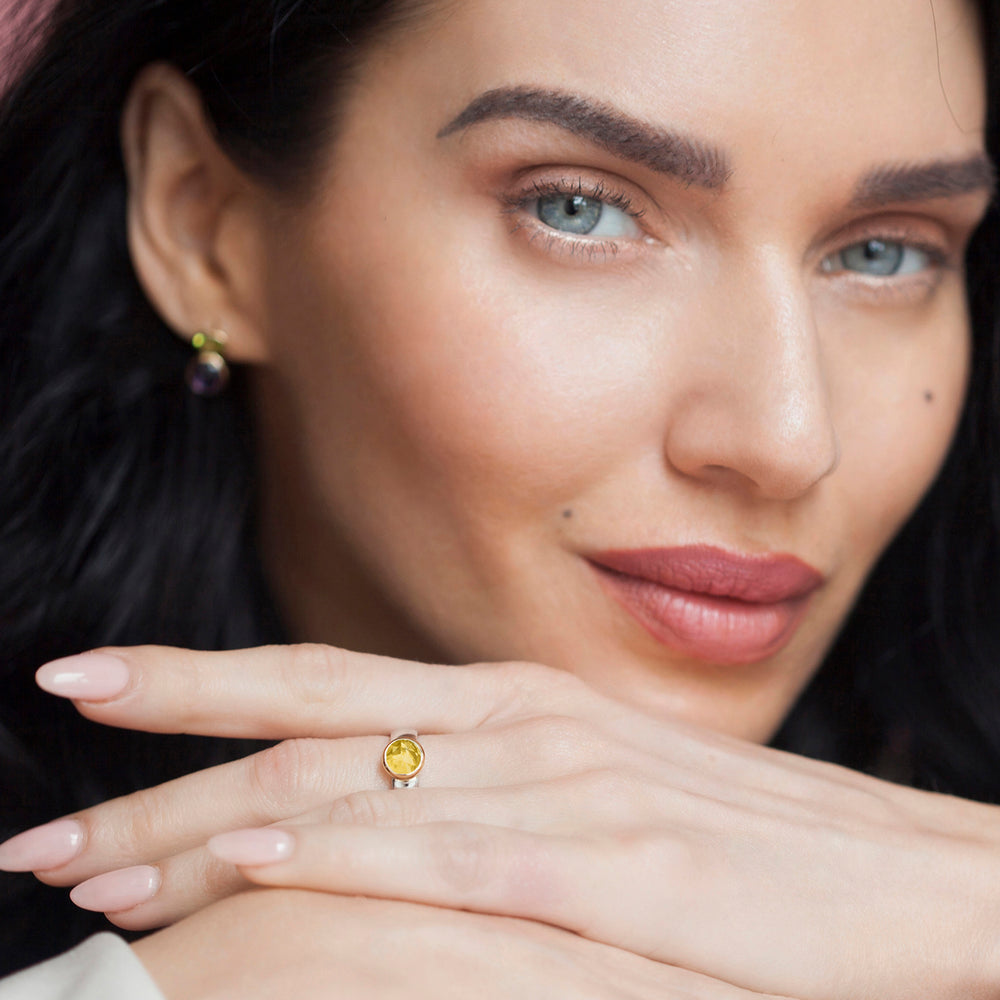 Model wearing a silver ring with a round yellow gemstone