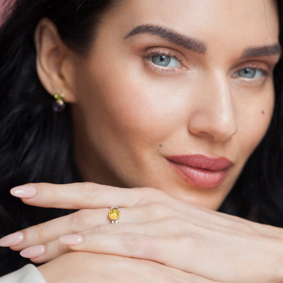 Model wearing a silver ring with a round yellow gemstone