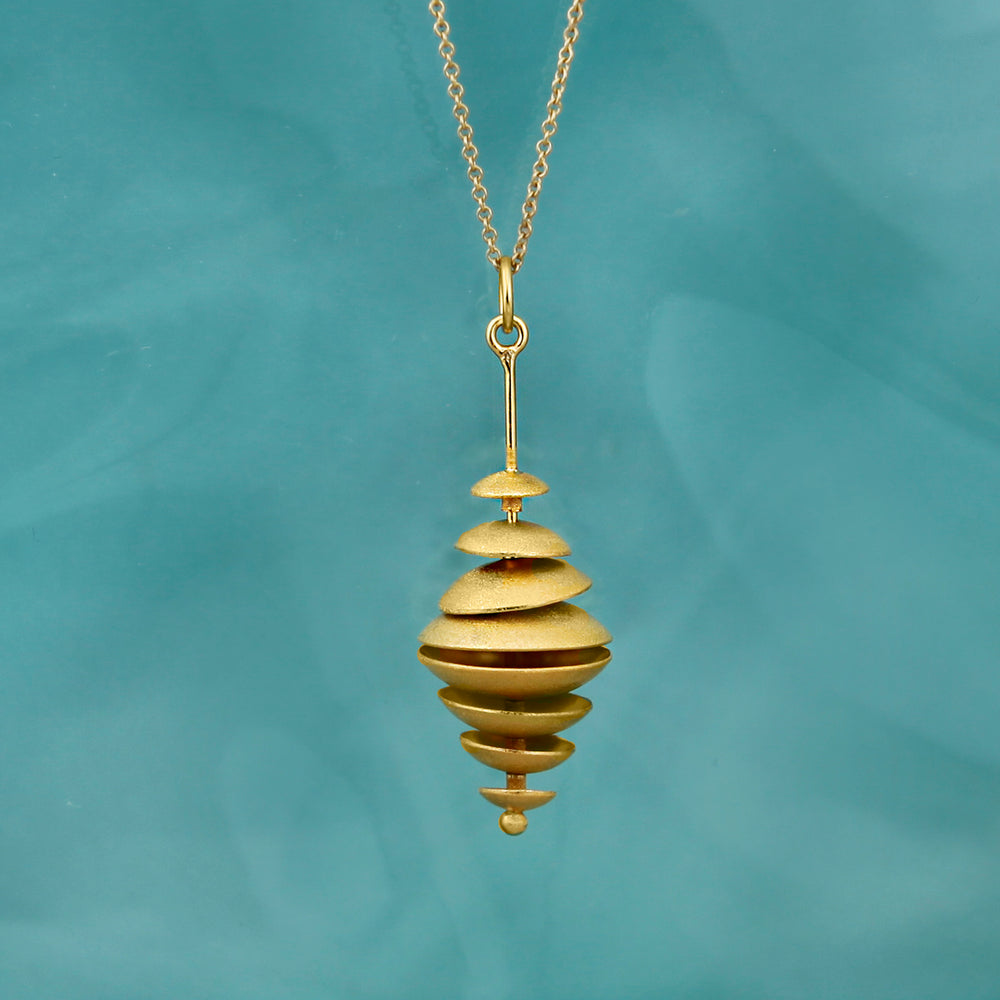 Gold multiple disk pendant necklace on a teal background