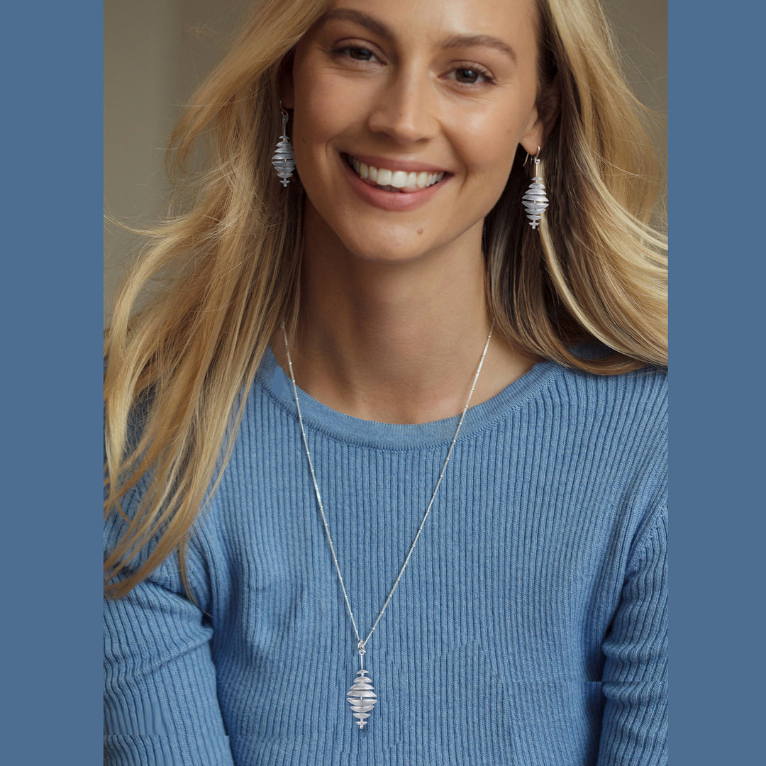 Woman wearing a blue sweater and silver necklace with matching earrings