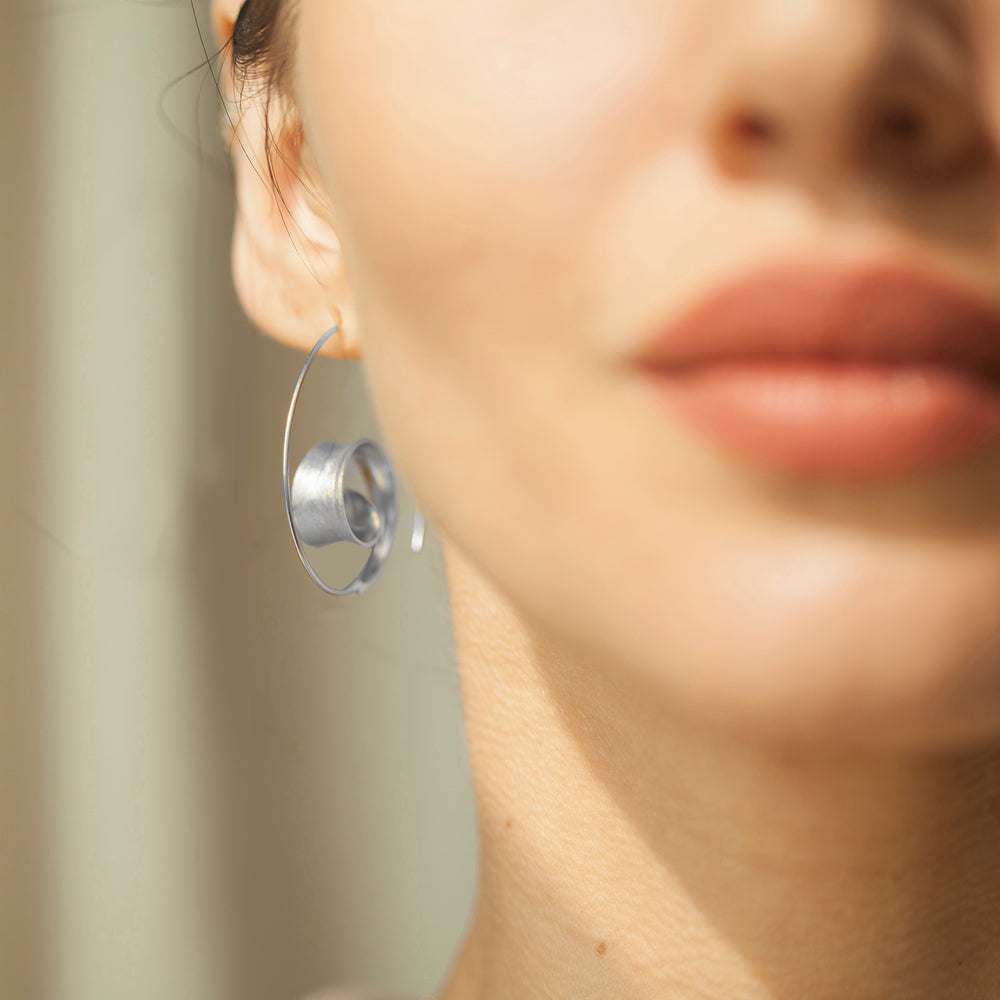 Close-up of a model wearing a silver threader hoop earring