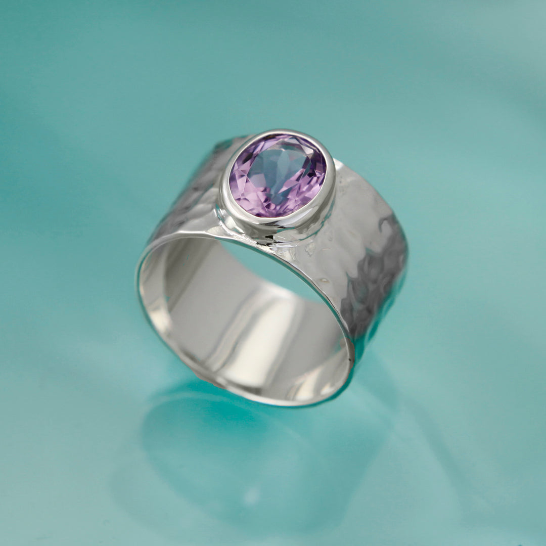 A large amethyst ring in textured sterling silver against an aqua background