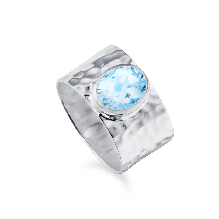 A large wide textured silver ring set with a big blue gemstone on a white background