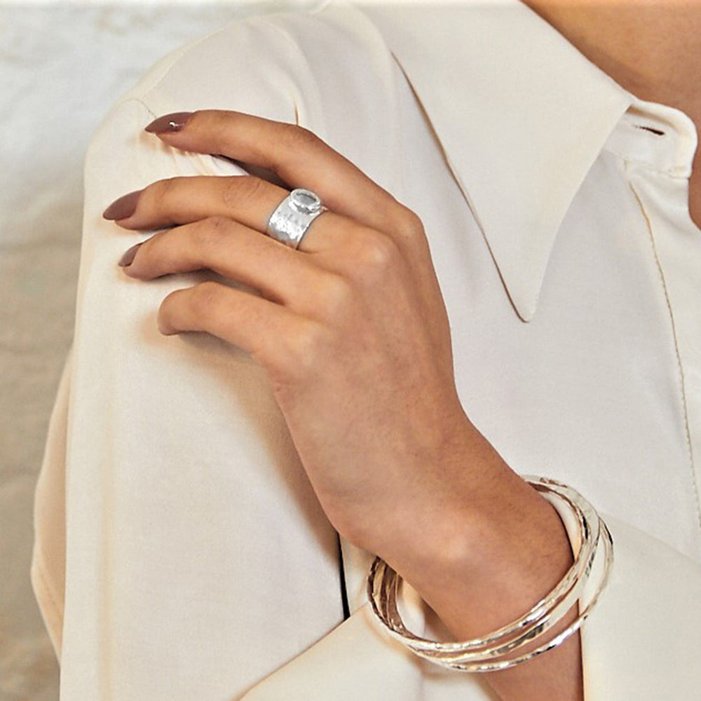 Model wearing a wide silver statement ring with a diamond like gemstone