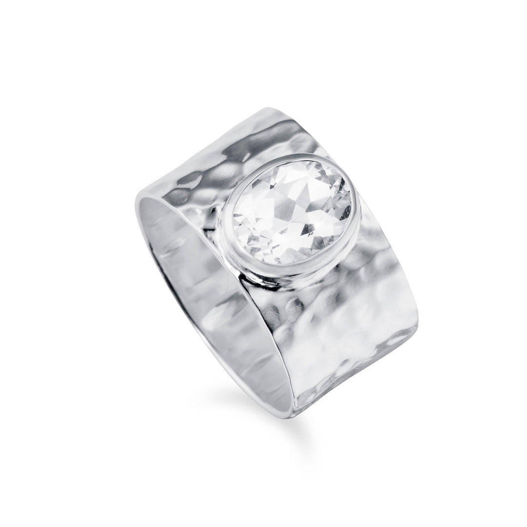 A silver wide band ring with a softly hammered texture and set with a large white gemstone on a white background