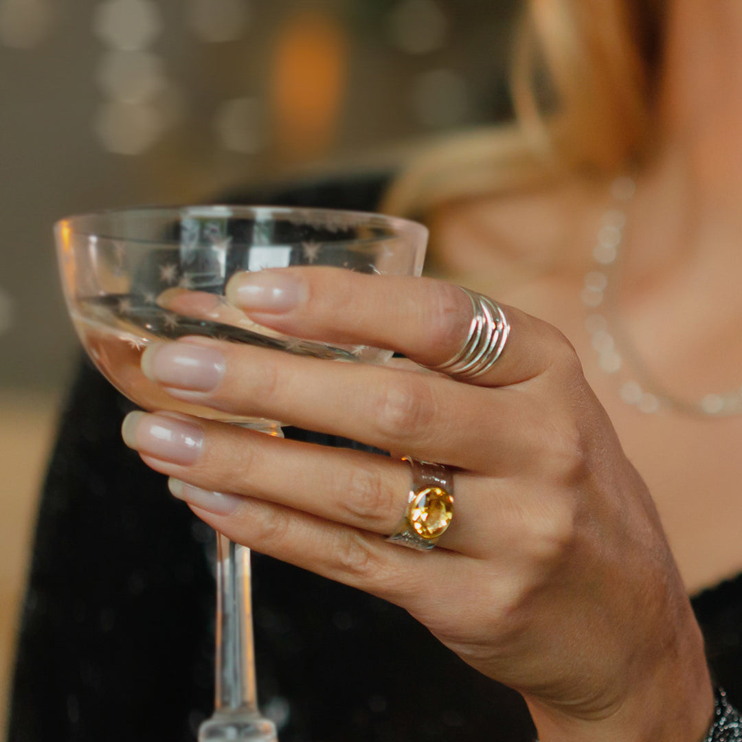 Woman wearing a citrine statement ring holding a glass of champaign