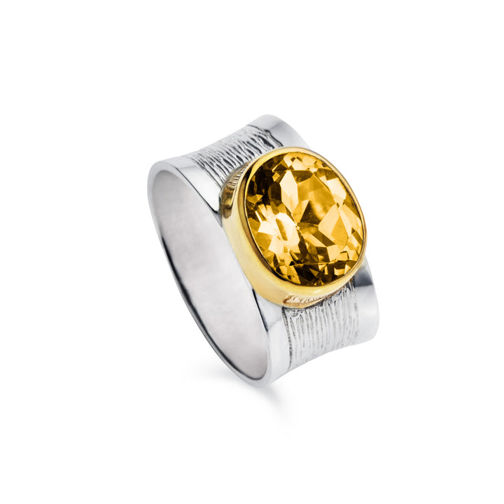 Wide silver ring with a large citrine gemstone and a gold bezel on a white background