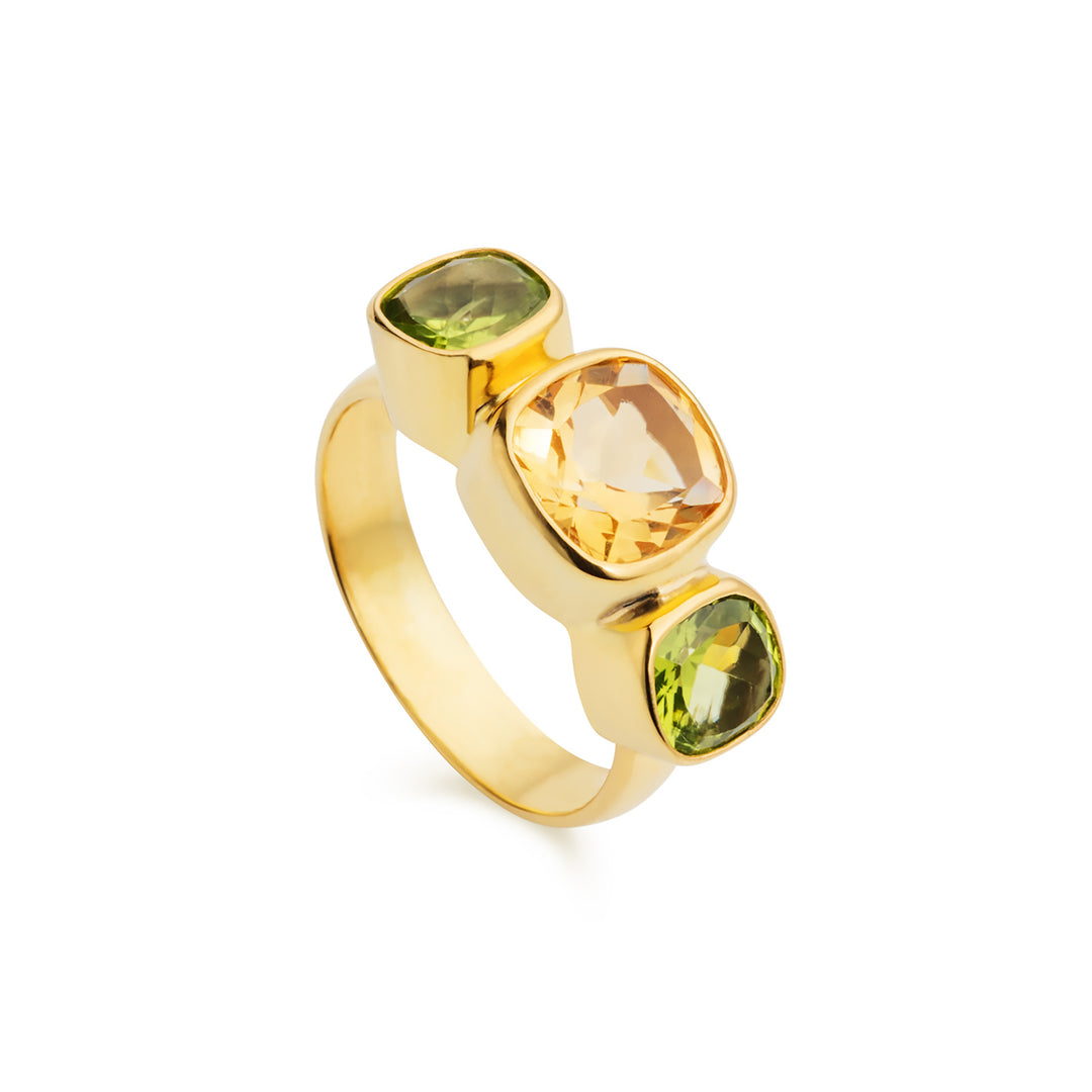 A gold ring with natural golden citrine set between two green peridot stoes on a gold band