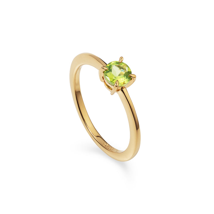 A gold ring with a green peridot gemstone in the center, on a white background.