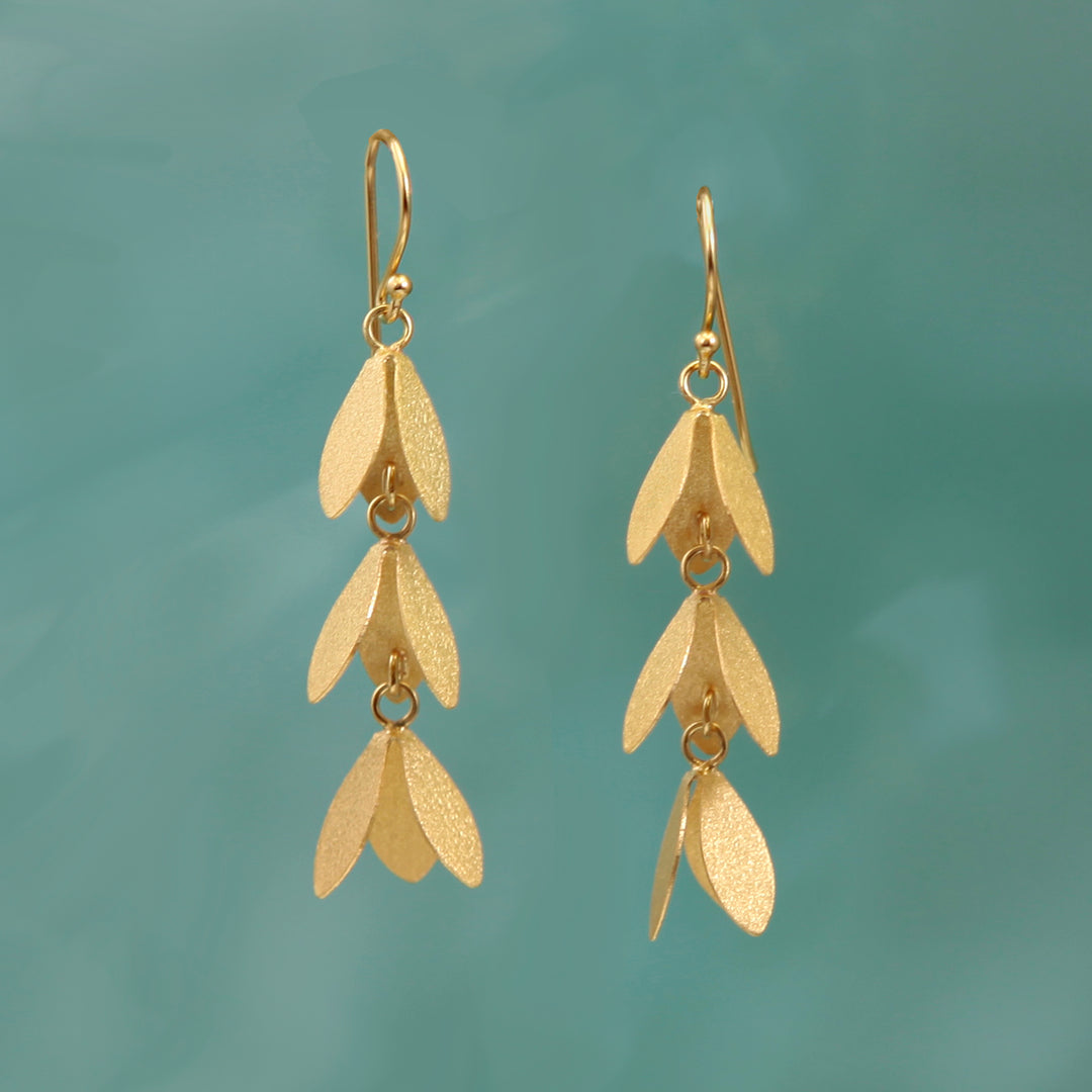 Gold vermeil long drop catkin flower earrings on a turquoise background