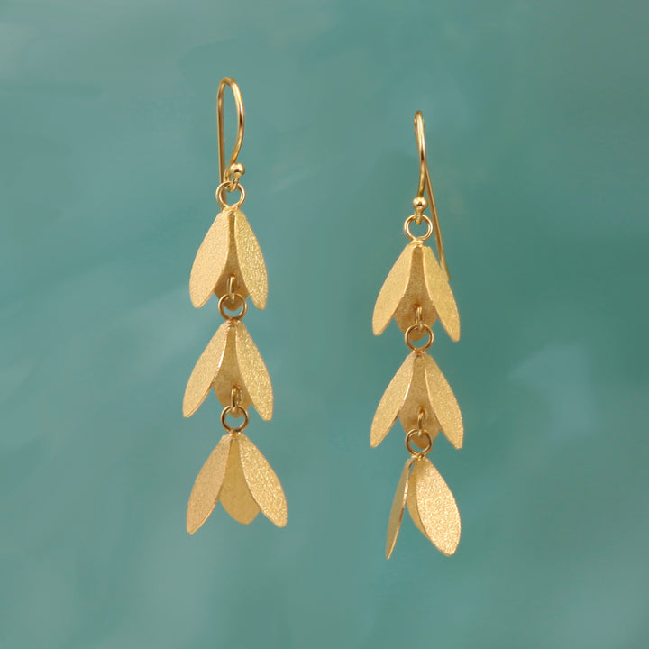 Gold vermeil long drop catkin flower earrings on a turquoise background