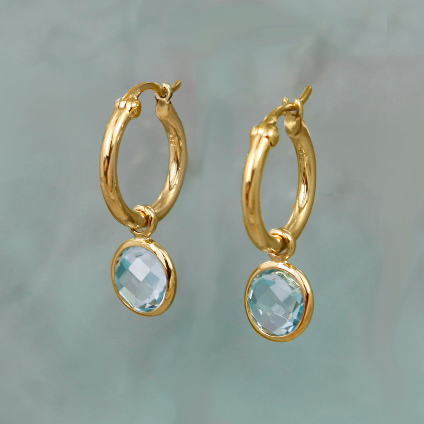 Staged Shot of Gold and Blue Topaz Huggie Hoop Earrings
