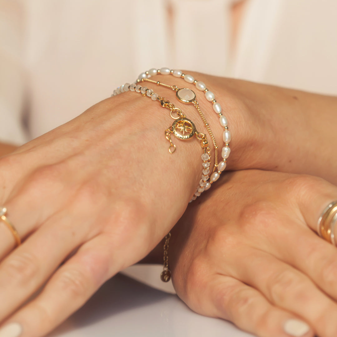 Model Wearing Gold Moonstone and pearl Beaded Bracelets ono her wrists.